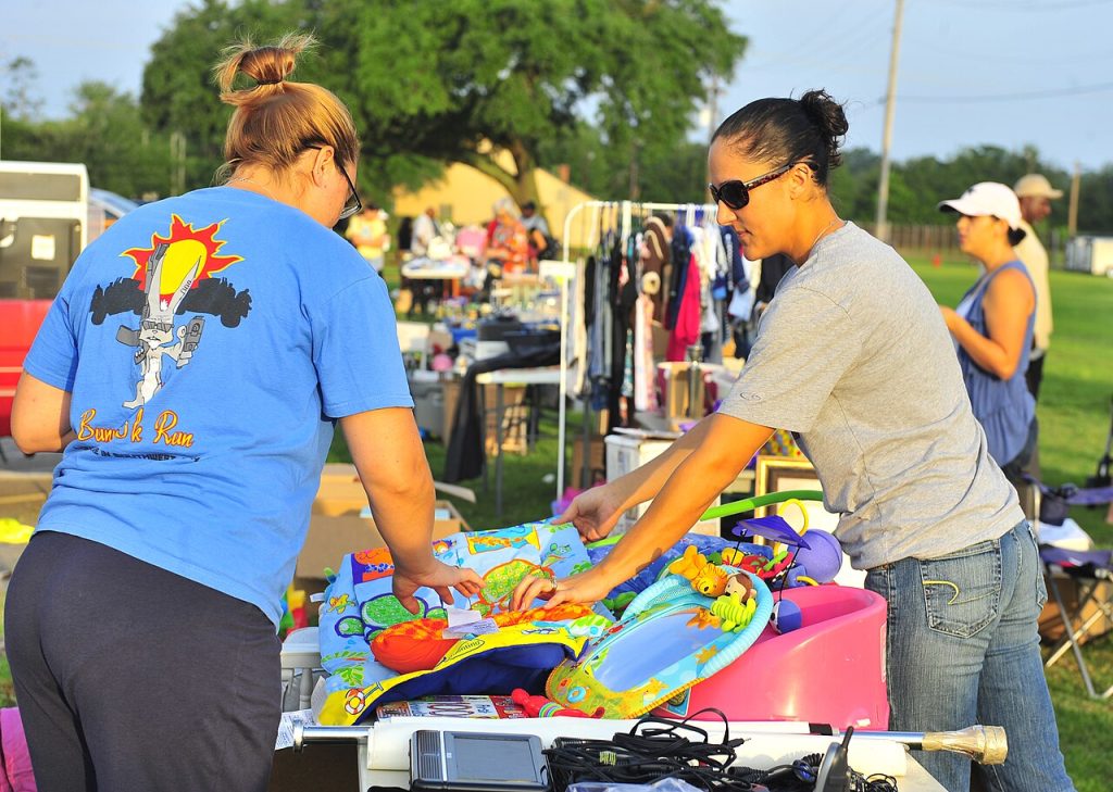 A seller showing a customer an item at a yard sale