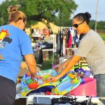 A seller showing a customer an item at a yard sale