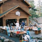 Yard sale with tables of household items in front of a house