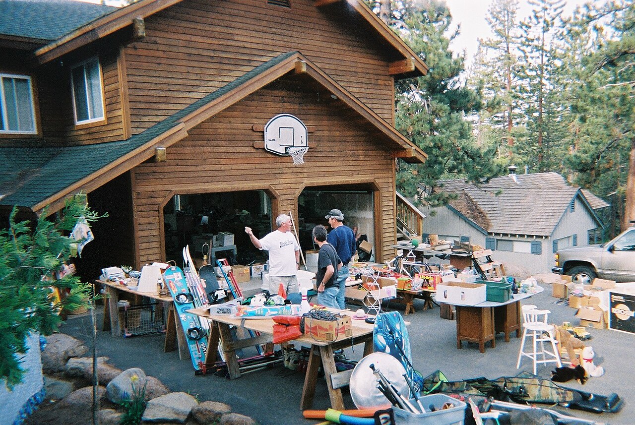 Yard sale with tables of household items in front of a house